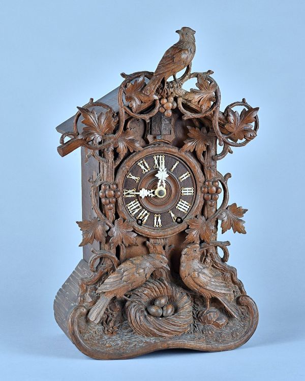 A German carved fruitwood 'Cuckoo' clock  By Beha, Late 19th Century  With carved cresting piece, stamped above the movement  BEHA and with printed pa