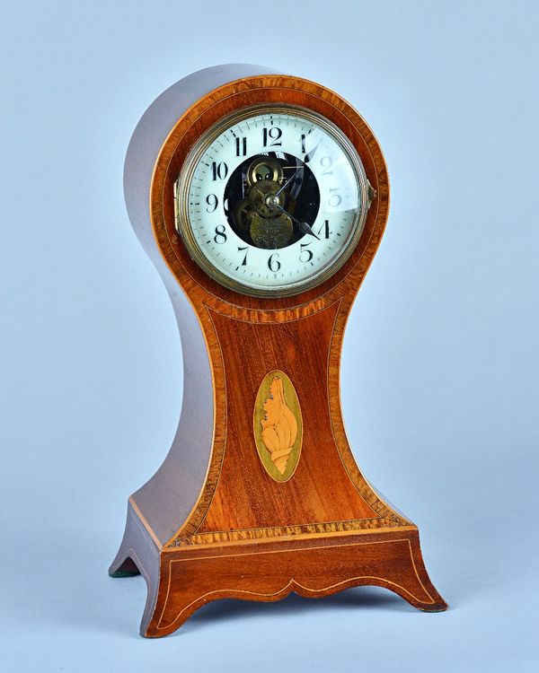 An unusual Eureka Clock Company Edwardian mahogany, crossbanded and line-inlaid, balloon-shaped mantel timepiece No 4227The case inlaid with a conch s