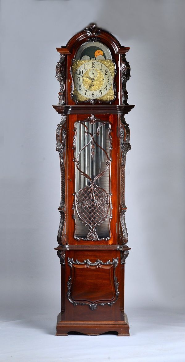 A large Edwardian mahogany three train quarter-chiming Longcase clockThe case carved all over with foliage, with an arched hood above glazed door and