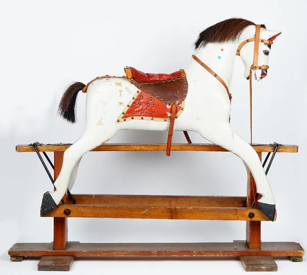 A wooden grey painted rocking horse, early 20th century, on a stained pine base, 114cm wide x 100cm high.