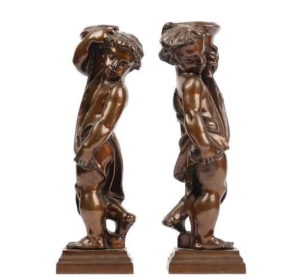 In the manner of Alfred Stevens (1817-1875), a pair of bronze fire dogs, modelled as putti, on stepped rectangular plinths, 40cm high.