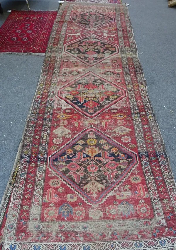 A Hamadan runner, Persian, the madder field with four bold dark brown diamonds, supporting flowerheads, a pair of white horses, a flower border, 352cm