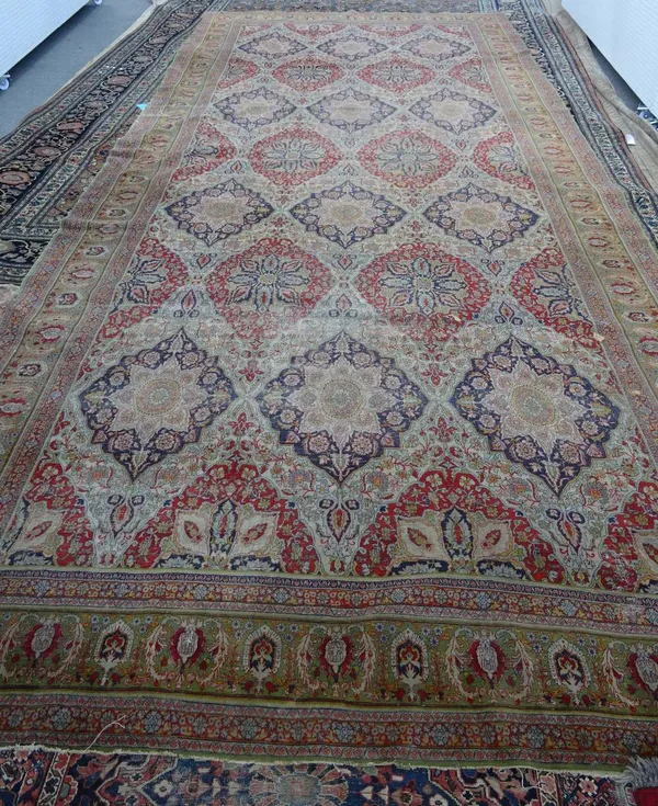 A Tabriz Kelleh carpet, Persian, the field with an all over design of stylised diamonds bearing medallions, in madder or indigo; a sage palmette, leaf