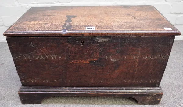 An oak planked coffer, 17th century, of small proportions, the moulded hinged top above a chip carved front on a shaped apron stand, 60.5cm wide x 30.