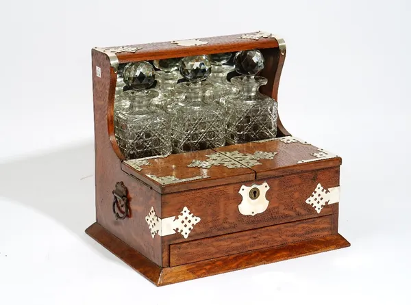 An Edwardian silver metal mounted oak tantalus with lift top compartment over drawer, 36cm wide x 33cm high.