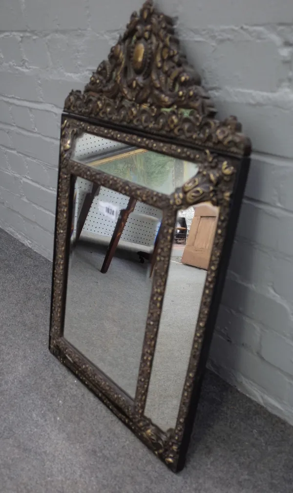 A 19th century Dutch repousse brass cushion framed mirror with arched crest, 46cm wide x 74cm high.