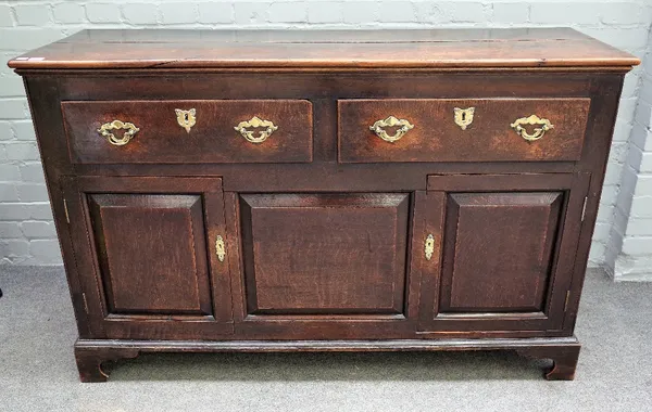 An oak low dresser, 18th century, of panelled construction, with two drawers and cupboard below, on bracket feet, 145cm wide x 51cm deep x 91cm high.