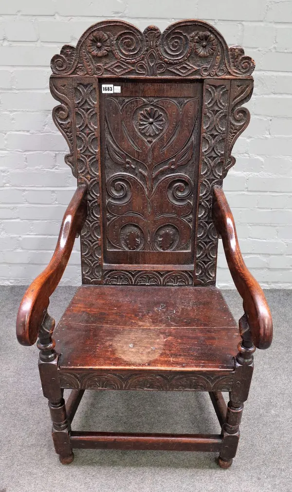 A mid-17th century and later carved oak panel back Wainscot open armchair on block and turned supports, 57cm wide x 118cm high.