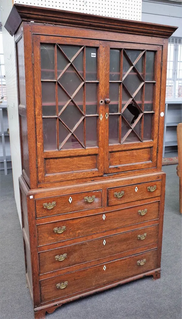 A mid-18th century provincial oak display cabinet chest with a pair of astragal glazed doors over two short and three long graduated drawers on bracke