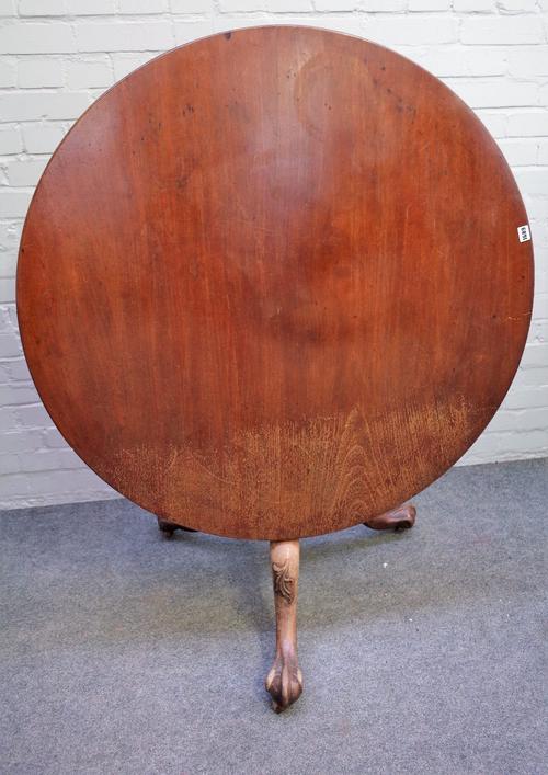 A mid-18th century mahogany supper table, the circular tilt-top on a birdcage and baluster turned pillar, the shell and leaf carved tripod base termin