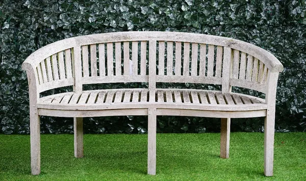 A teak semi-elliptic garden bench of slatted construction on block supports, 160cm wide x 87cm high