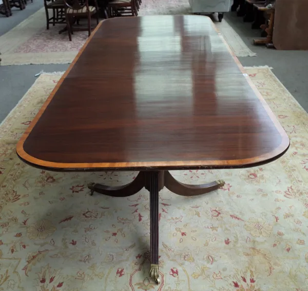 A George III style satinwood banded mahogany triple pillar extending dining table, on ten downswept supports, 107cm wide x 274cm long.