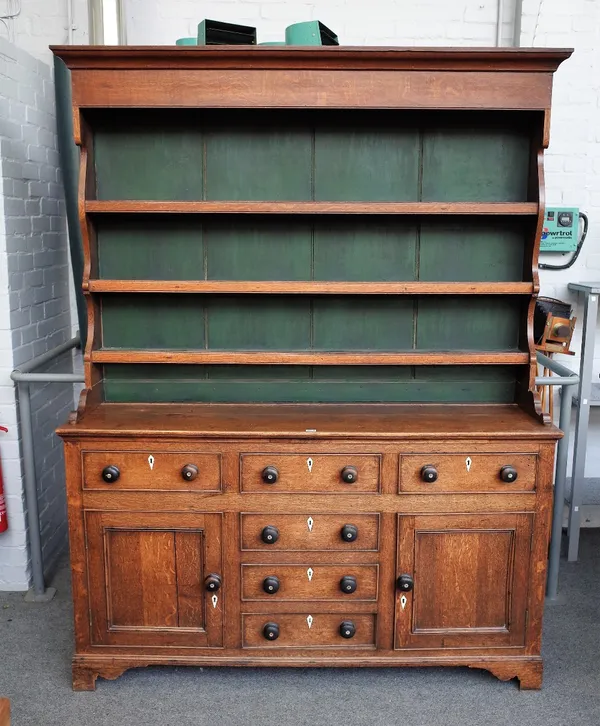 A late George III oak dresser, the enclosed three tier plate rack, over six frieze drawers, flanked by cupboards on bracket feet, 168cm wide x 213cm h