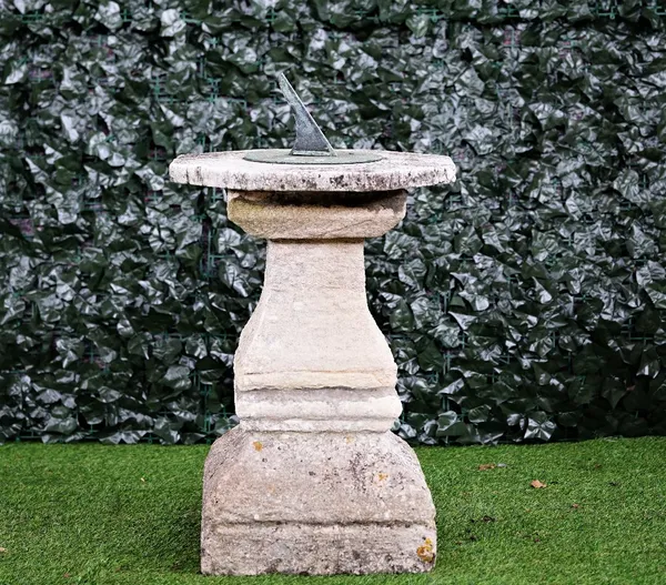 A cast bronzed sundial on a stone square baluster column, 80cm high