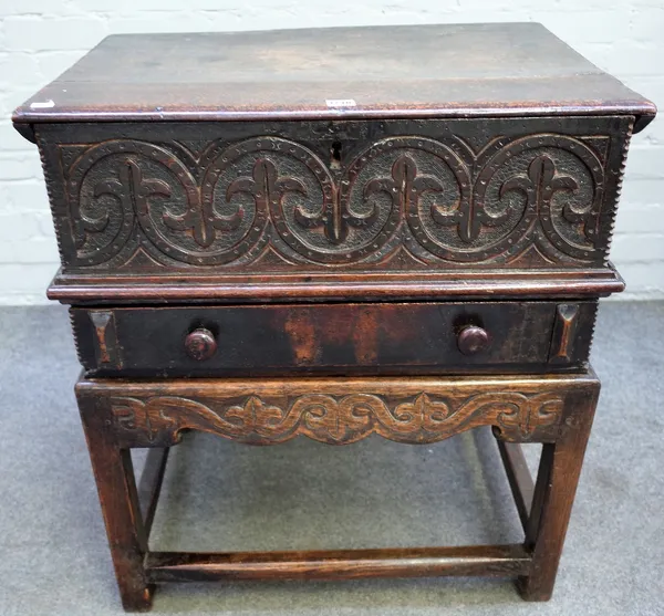 An oak bible box, 17th century, the hinged top with chip carved edge, the front carved with repeated scroll work, a drawer below, on a reproduction oa