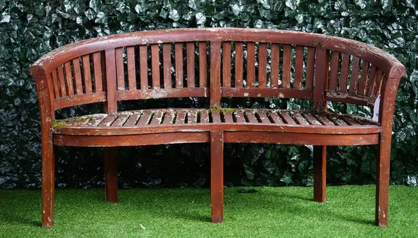 A teak curved garden bench of slatted construction, 160cm wide x 84cm high.