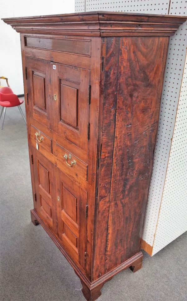 A George III style oak cupboard, the ogee moulded cornice above two pairs of raised and fielded panel doors, with two drawers between, on shaped apron