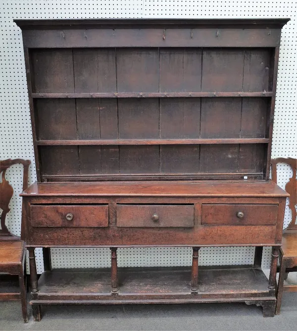 A George III oak dresser, the boarded shelved rack with iron hooks, the projecting base with three frieze drawers, on gun barrel turned legs united by