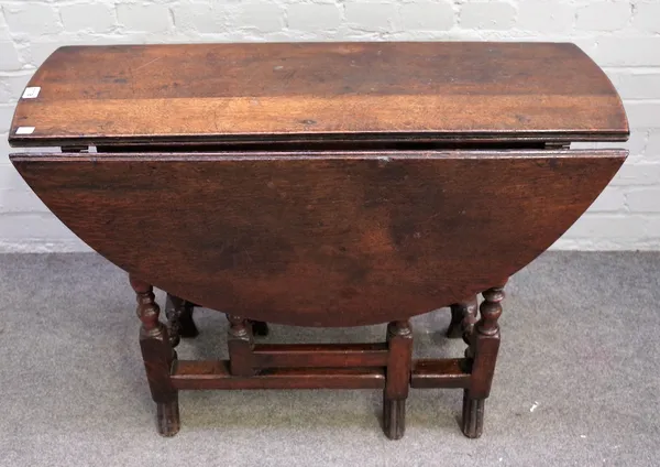 A late 17th century style oak gateleg table, with hinged circular top, end drawer, on baluster turned legs with splayed feet, 93cm wide x 34cm deep x