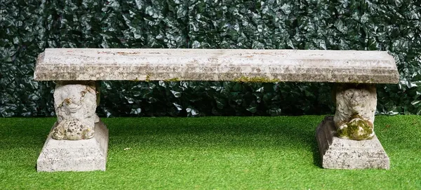 A reconstituted stone curved garden bench, on a pair of recumbent lion supports, 175cm wide x 50cm high