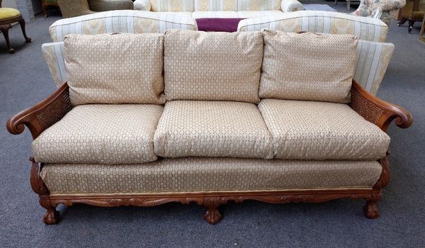 An early 20th century carved walnut framed double bergere three piece suite, to comprise;  a sofa, 195cm wide x 83cm high, and a pair of armchairs, 81