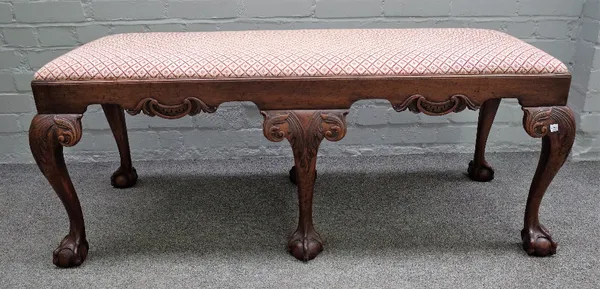 A George III style mahogany rectangular footstool, with carved frieze on six claw and ball supports, 130cm wide x 51cm high.