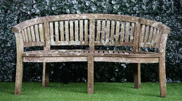 A teak semi-elliptic garden bench of slatted construction, 160cm wide x 86cm high, together with a matching low table, 118cm wide x 51cm high, (AF).