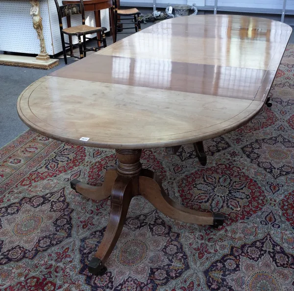 A Regency style mahogany boxwood strung and banded triple pillar dining table, 19th century, with 'D' shape ends and two extra leaves, the ring turned