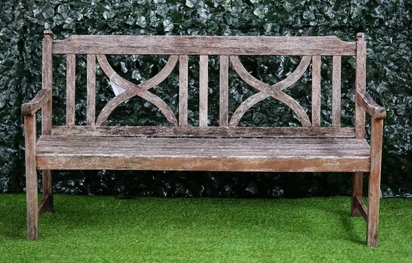 A teak garden bench with double X-framed back and slatted seat, 151cm wide x 86cm high.