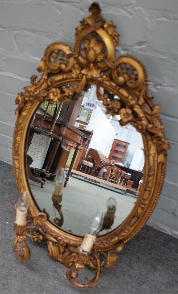 A Victorian gilt framed girandole wall mirror with opposing 'C' scroll crest above the oval mirror and a pair of candle sconces, 50cm wide x 81cm high