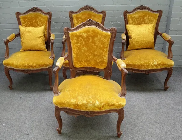 A set of four Louis XV style walnut framed open armchairs with 'C' scroll crest and serpentine seat on scroll supports, 63cm wide x 93cm high, (4).