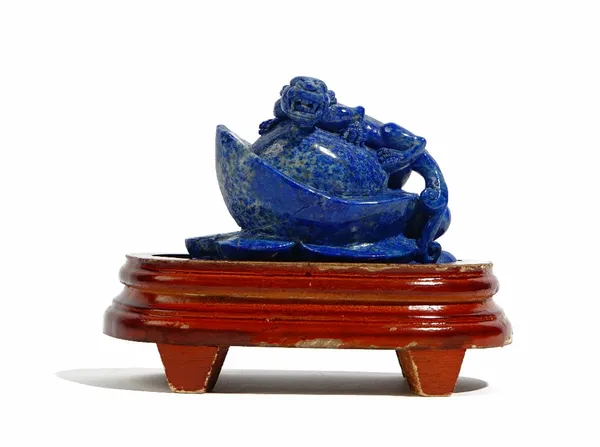 A Chinese lapis lazuli carving, depicting a chilong clambering on a flower or fruit, 8.75cm. high, wood stand, (2).