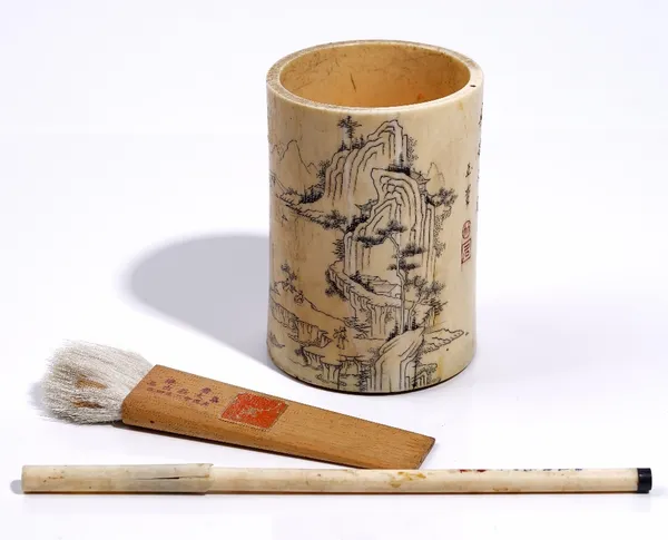 A Chinese ivory brush pot, Qing dynasty, decorated in black with figures and buildings in a mountainous river landscape, the reverse with lines of cal