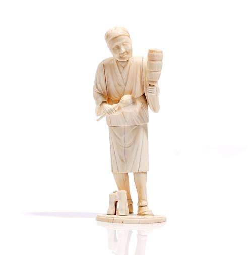 A Japanese ivory sectional okimono of a musician, Meiji period, carved standing with a gourd vase and stick in his right hand and a shaker in the othe