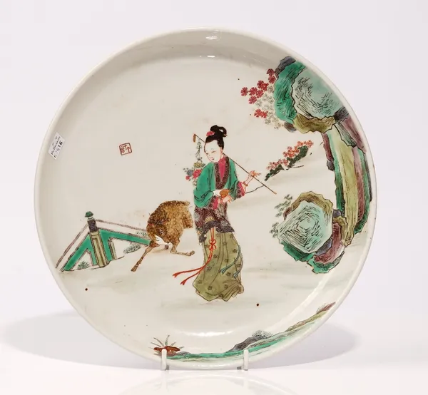 A Chinese polychrome dish, 20th century, enamelled with a woman with a deer in a landscape, 27cm. diameter.