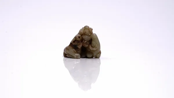 A Chinese jade group of two recumbent goats with lingzhi, Qing dynasty, the stone of greyish celadon tone with brown inclusions, 5cm. wide.