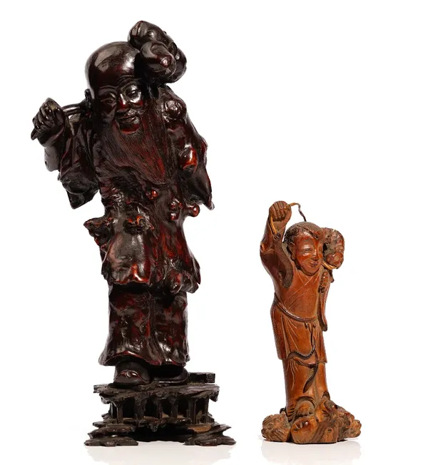 A Chinese rootwood carving of a bearded man, late 19th/20th century, carved standing  carrying a branch of fruiting peaches over his shoulder, 34cm. h