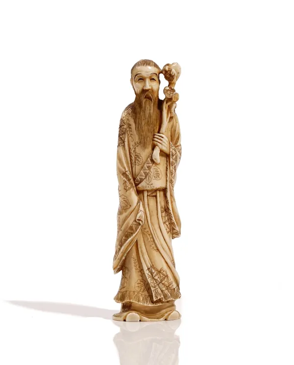 A Japanese ivory okimono, Meiji period, carved as a bearded  man standing in long robes with a staff, signed; also a smaller ivory okimono of a fisher