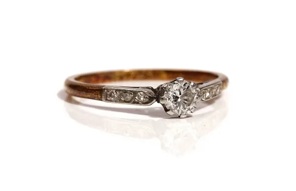 A gold and platinum ring, claw set with the principal circular cut diamond at the centre, between diamond set three stone shoulders, detailed 18 CT PL