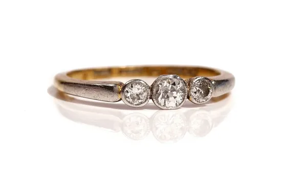 A gold and platinum, diamond set three stone ring, collet set with a row of cushion shaped diamonds and with the principal diamond mounted to the cent