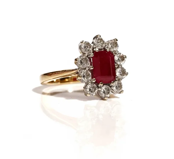 A gold, ruby and diamond set cluster ring, claw set with the cut cornered rectangular ruby to the centre, in a surround of ten circular cut diamonds,