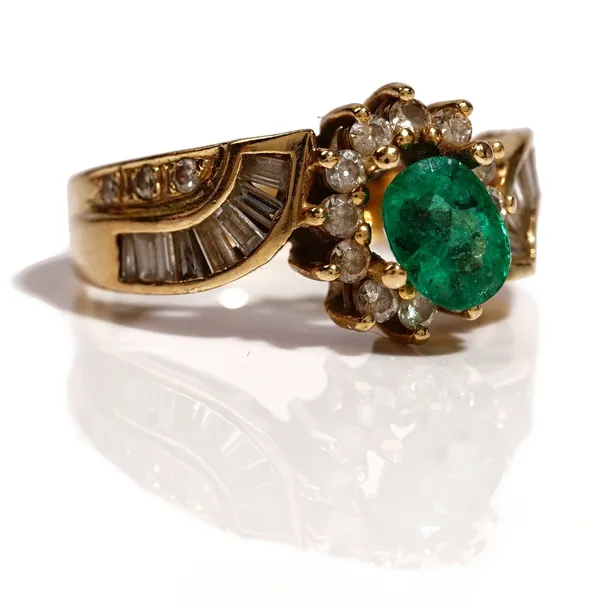 A gold, emerald and diamond ring, (the central oval cut emerald detached, but present), the mount with a surround of circular cut diamonds between bag