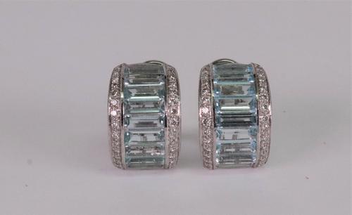 A pair of precious white metal, aquamarine and diamond set earclips of half hoop design, channel set with baguette cut aquamarines, between two rows o