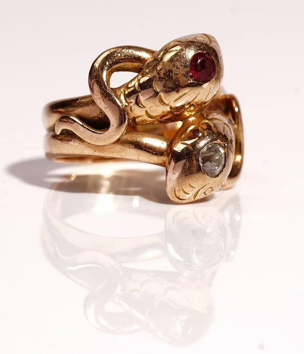 A gold, ruby and diamond ring, designed as two entwined snakes, mounted with a cushion shaped diamond and with a cushion shaped ruby, detailed indisti