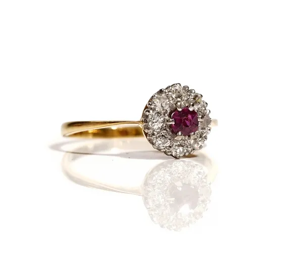 An 18ct gold, ruby and diamond set nine stone cluster ring, claw set with the cushion shaped ruby at the centre, in a surround of eight cushion shaped