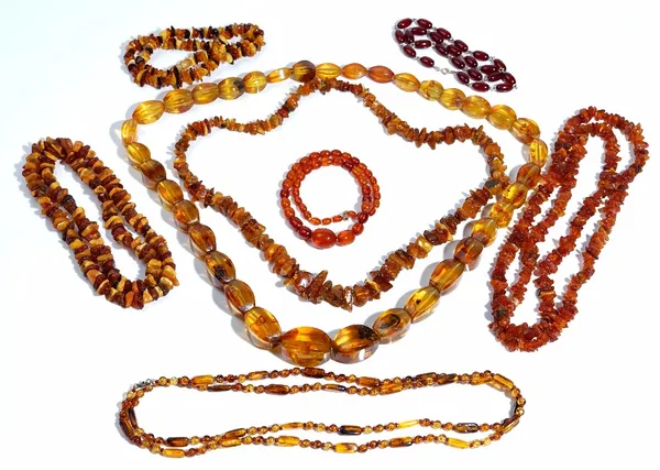 A single row necklace of graduated oval varicoloured translucent amber beads, on a gold clasp, detailed 375, three single row necklaces of rough amber