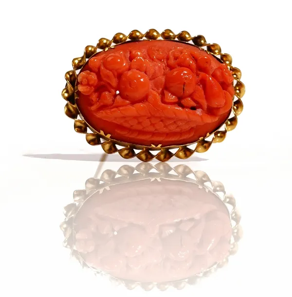 An oval coral brooch, carved as a basket of flowers, the setting decorated with a ribbon twist surround.