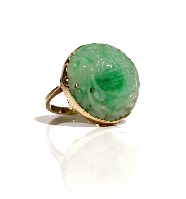 A 9ct gold mounted jade ring, the circular Asian jade with carved and pierced decoration, Birmingham 1984, ring size N, gross weight 11 gms.