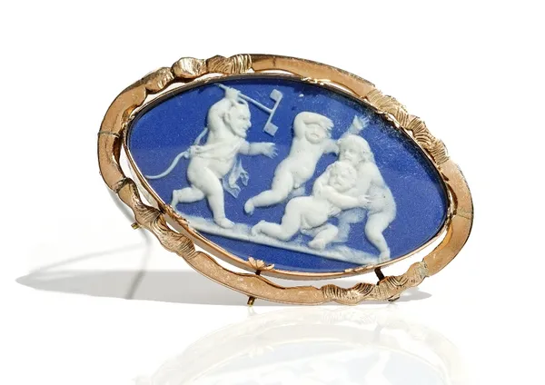 A gold mounted oval blue and white jasperware cameo brooch, designed as a group of three putto, being chased by a devil, within a shaped oval surround