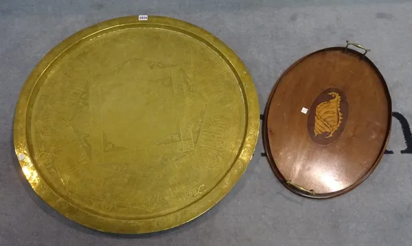 A large early 20th century Eastern embossed brass circular tray, 79cm diameter and a 19th century inalid mahogany oval serving tray, 58cm wide (2).